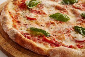 Pizza con ingredientes naturales tomate, jamón, verduras, champiñones, salami.